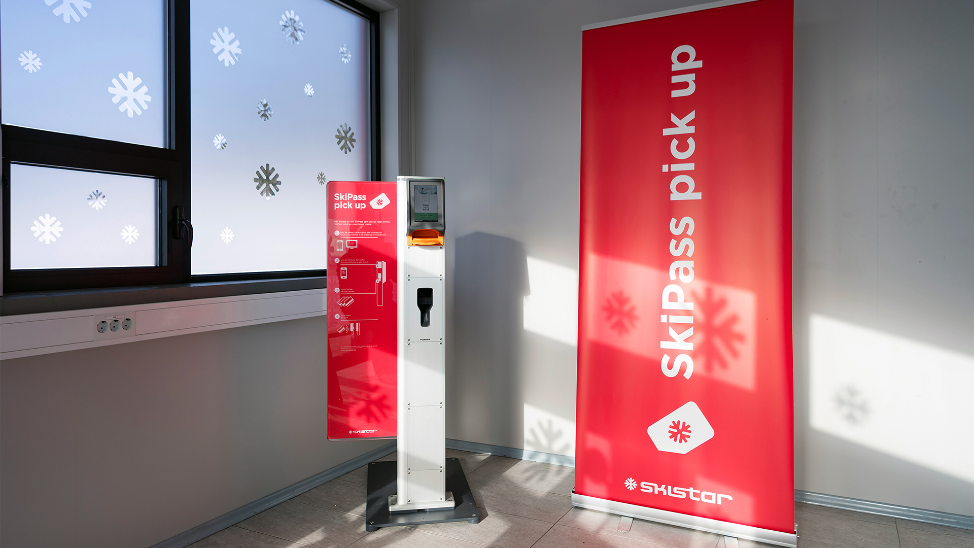 SkiPass-automat från SkiStar i ett rum med fönsterdekorationer av snöflingor