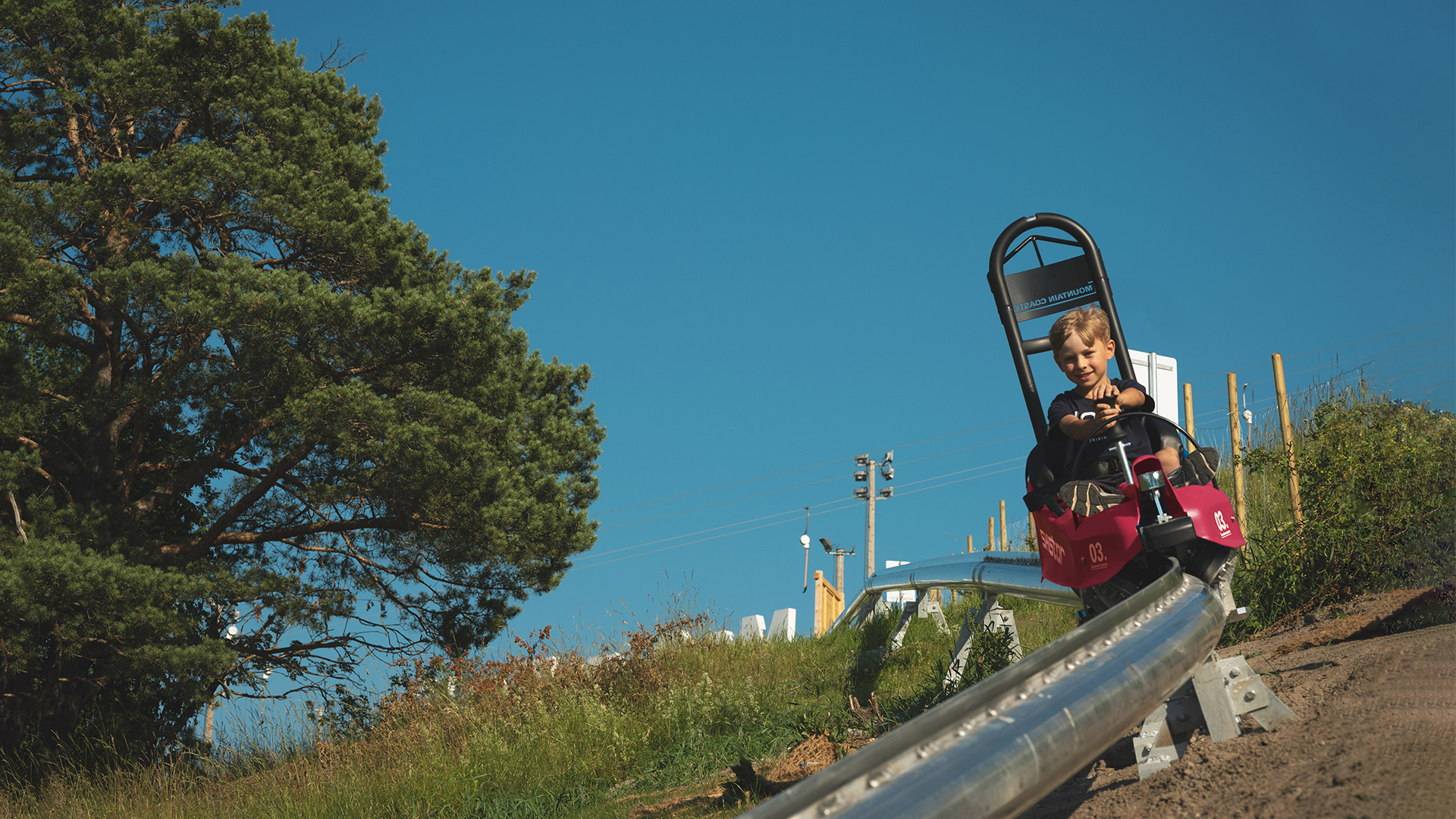 En person som åker i en mountain coaster, rodel, i fjällen.