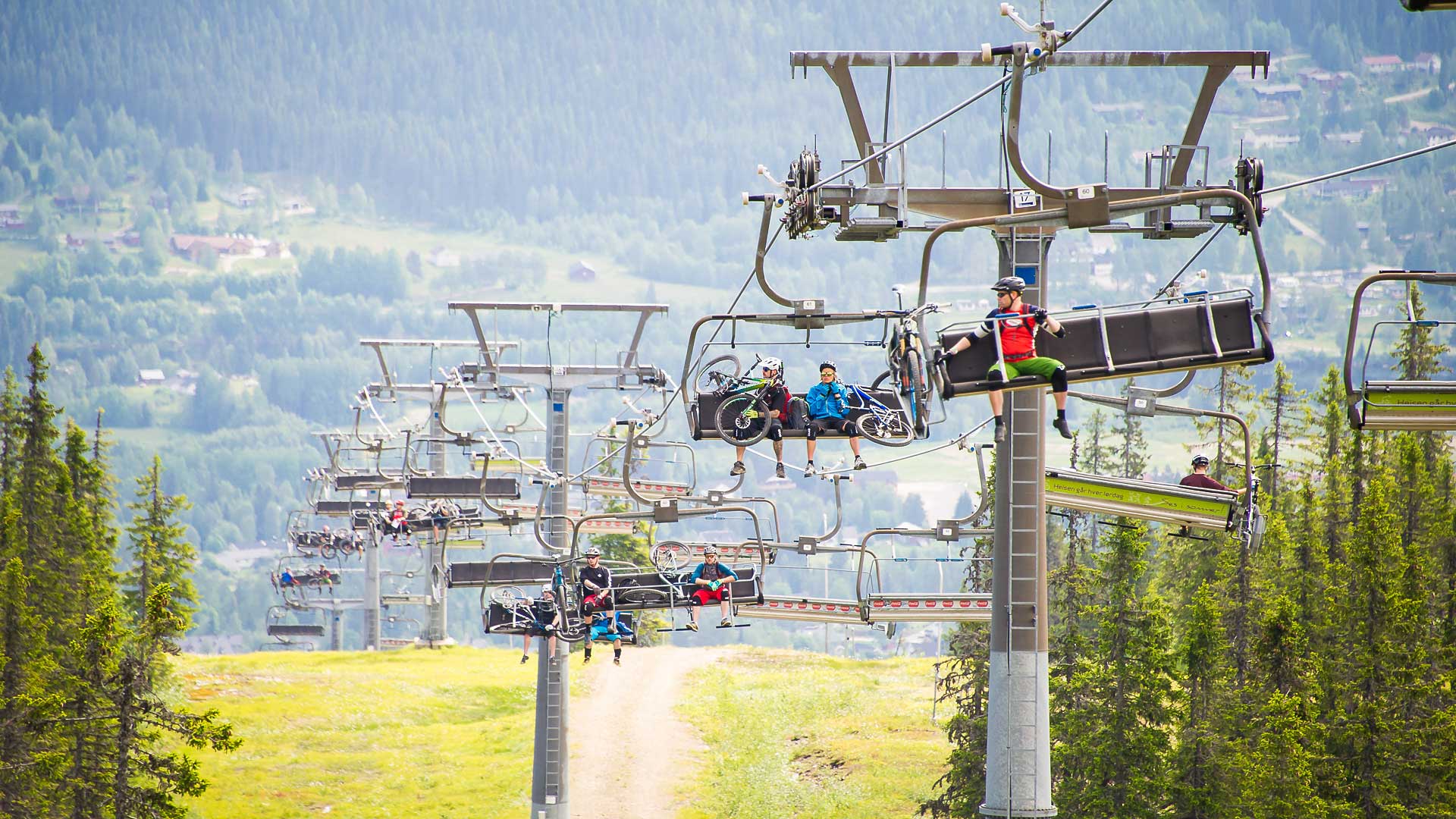 Sittliftar i fjällen på sommaren i Trysil, med människor som sitter i liftarna.