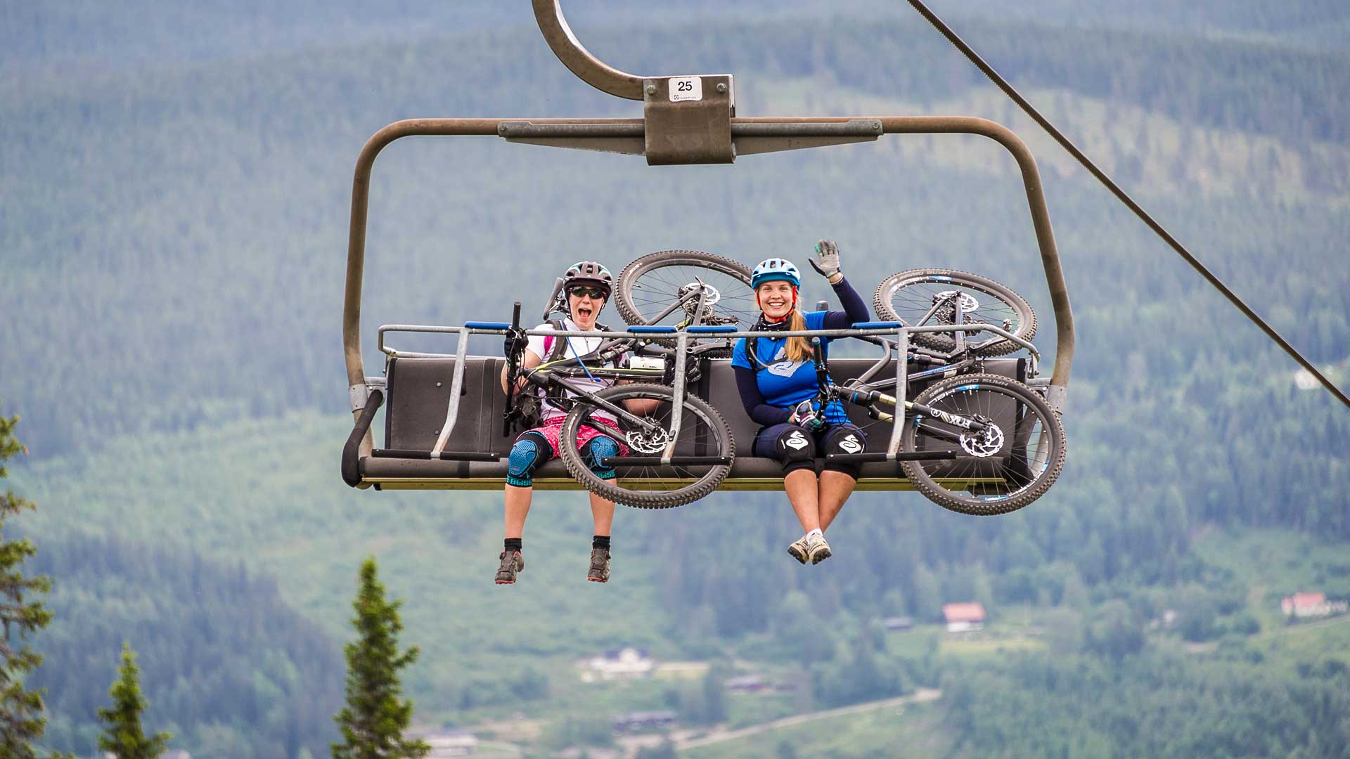 Två cyklister i fjällhiss med mountainbikes i en bergig landskap
