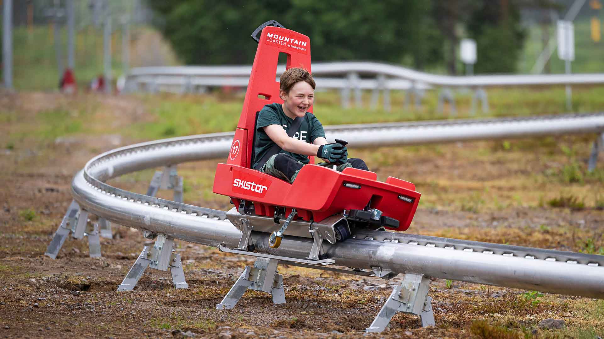 Pojke åker röd berg- och dalbanevagn på räls i fjällen, Skistar, sommaraktivitet