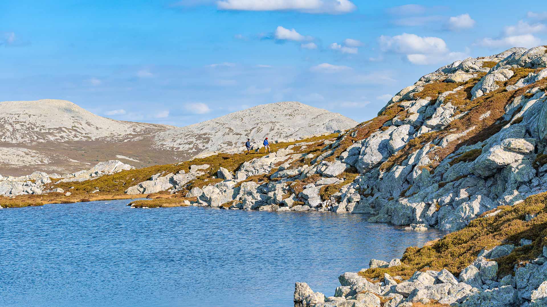 Berglandskap i Norge med klar sjö, klippiga sluttningar och blå himmel. Perfekt för vandring och naturskön utsikt