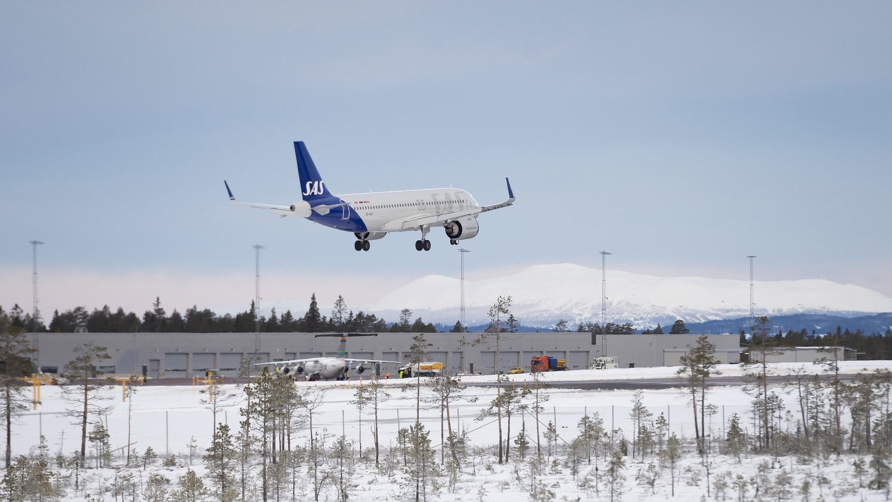 Flygplan från SAS landar på en snötäckt flygplats i Sverige med fjäll i bakgrunden