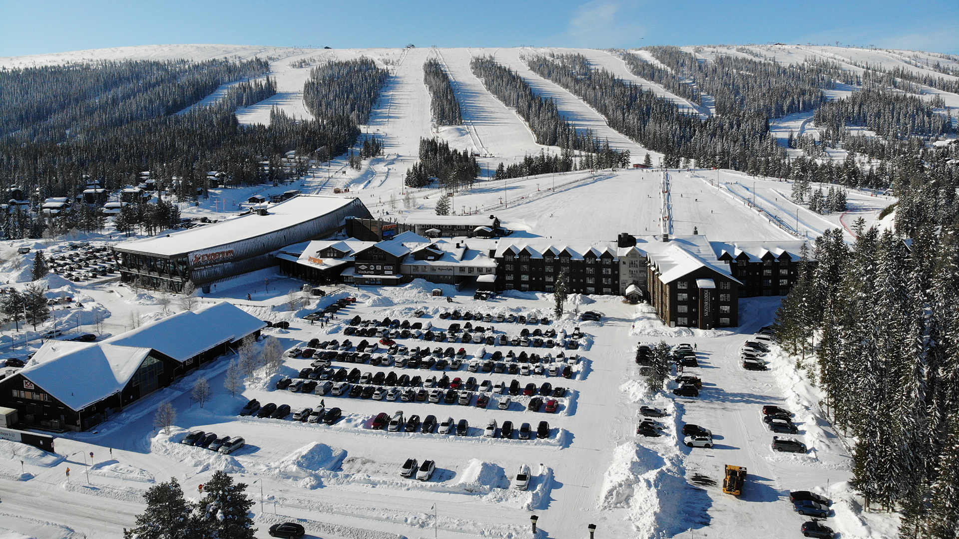 Winter panorama of a ski resort with snow-covered slopes, hotels, and parking in Sweden
