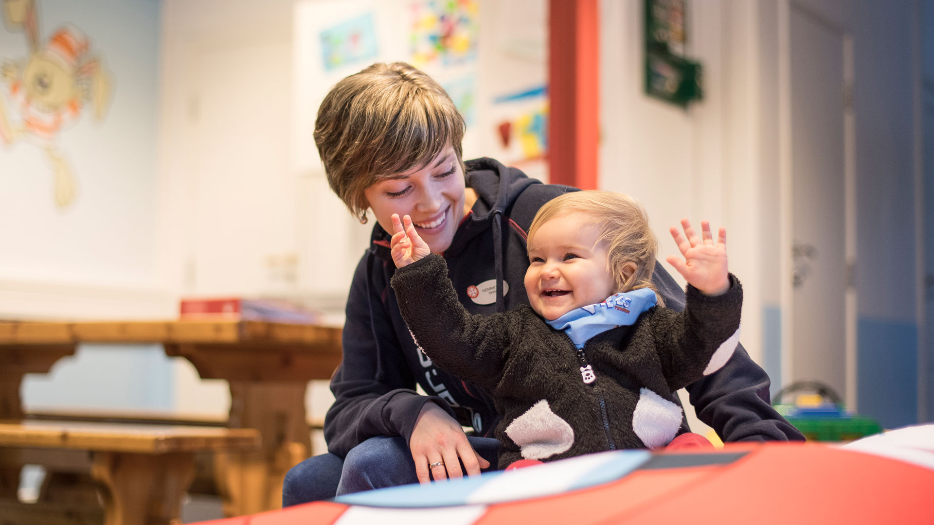 Woman and smiling baby in a child-friendly place, indoors, playing together